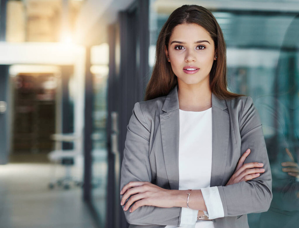 Тебе нужна уверенность в корпоративном мире. Портрет привлекательной молодой предпринимательницы, стоящей со скрещенными руками в офисе - Фото, изображение