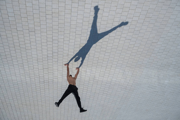 Shirtless man walks on his hands outdoors. View from above - Φωτογραφία, εικόνα