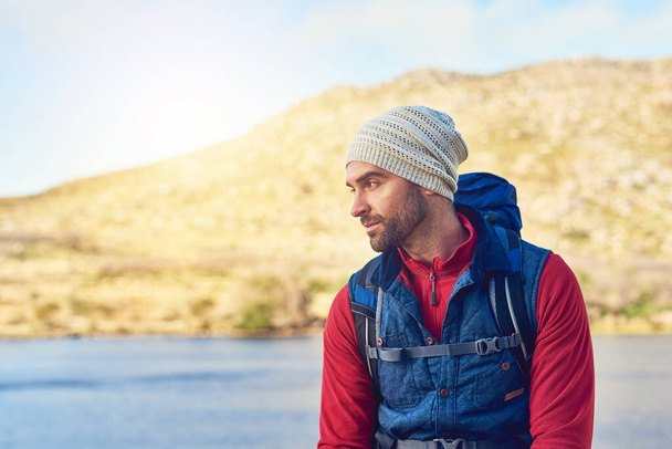 Fresh air helps him clear his mind. a thoughtful hiker admiring the view of a lake on a sunny day - Foto, imagen
