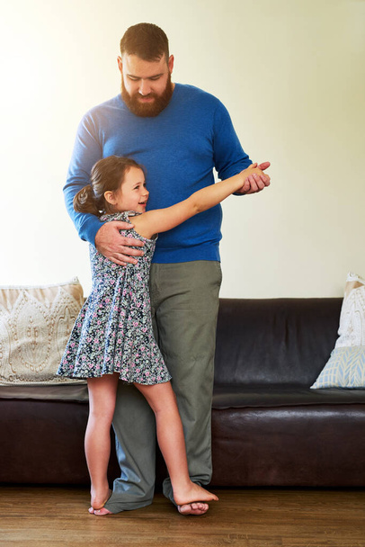 Зробимо батьківство крок за кроком. чарівна маленька дівчинка танцює з батьком вдома
 - Фото, зображення