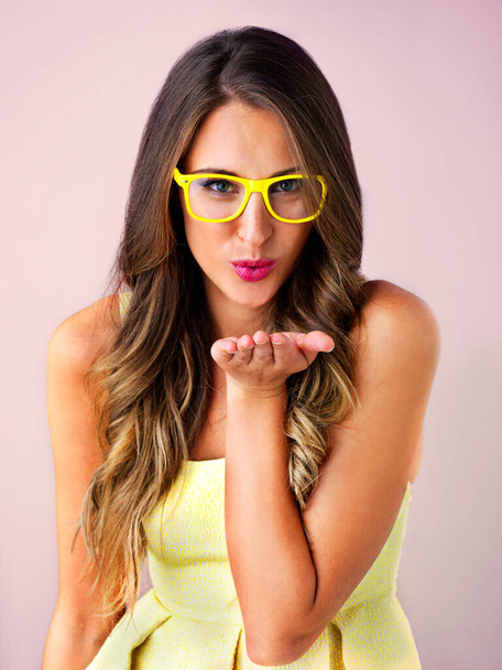 This one is for you. Studio shot of a beautiful young woman blowing a kiss against a pink background - Photo, Image