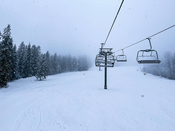 Ski Lift snowy mountain winter forest with chair lift At The Ski Resort in winter. Snowy weather Ski holidays Winter sport and outdoor activities Outdoor tourism skiing snowboarding - Fotoğraf, Görsel