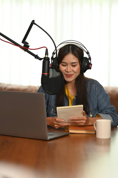 Asian content creator wearing headphone and talking through microphone for recording conversation for channel listeners. - Foto, immagini
