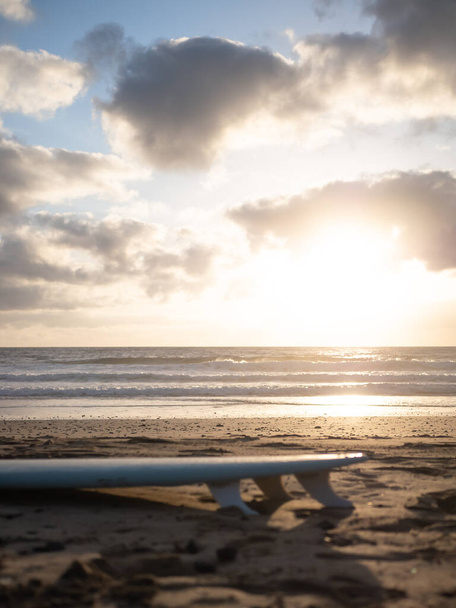 A surfboard lying on the beach at sunrise - Foto, Imagem