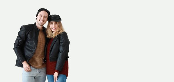Portrait of happy young couple in warm autumn clothes on light background with space for text - Fotó, kép