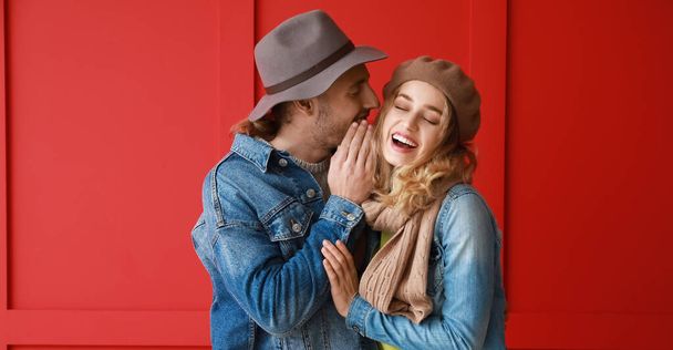 Happy young couple in warm autumn clothes on red background - Foto, Imagem