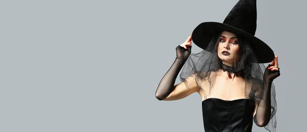 Beautiful woman dressed as witch for Halloween on grey background with space for text - Foto, immagini
