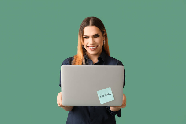 Transgender programmer with laptop on green background - Foto, Imagen