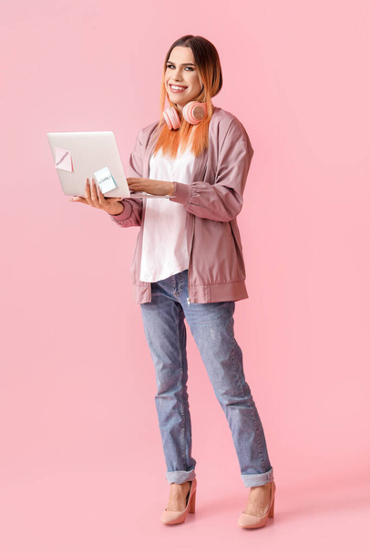 Transgender programmer with laptop on pink background - Фото, изображение