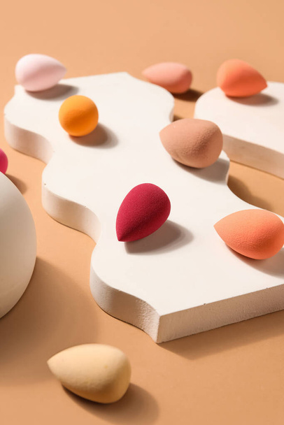 Stand with makeup sponges on beige background - 写真・画像