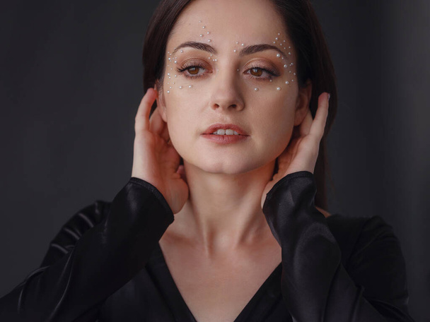 Beauty, fashion studio portrait of young woman in black dress with pearl makeup. Aesthetics of minimalism. Concept for spa, wedding salons, beauty treatments. - Fotó, kép