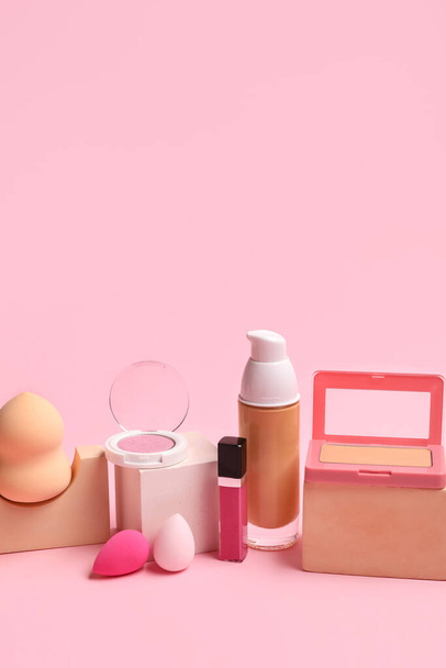 Makeup sponges with decorative cosmetics and blocks on pink background - Foto, afbeelding