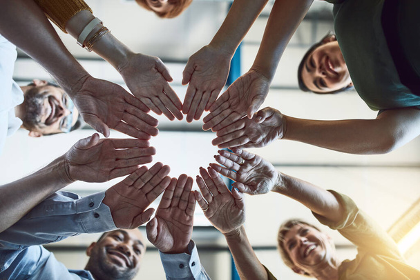 Get hands on in the pursuit of success. Low angle shot of a group of colleagues joining their hands in solidarity at work - Fotoğraf, Görsel