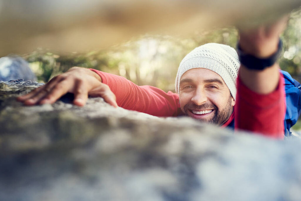 Im on my way to the top. Portrait of a happy hiker climbing over rocks on a mountain trail - Zdjęcie, obraz