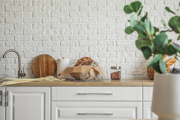 Καλάθι με καρβέλια φρέσκο ψωμί στον πάγκο στην κουζίνα - Φωτογραφία, εικόνα