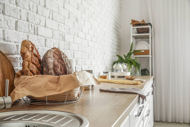 Basket with loaves of fresh bread on counter in kitchen - Valokuva, kuva