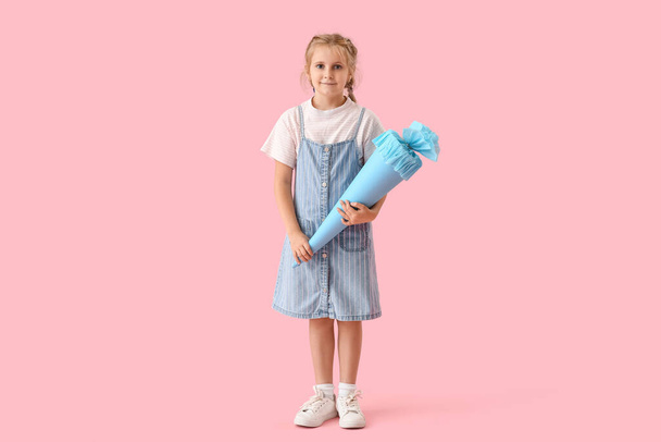 Cute little girl with blue school cone on pink background - Foto, Imagen