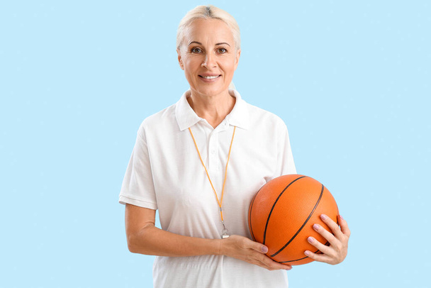 Mature PE teacher with ball on blue background - Foto, imagen