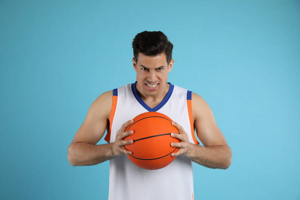 Basketball player with ball on light blue background - Foto, imagen