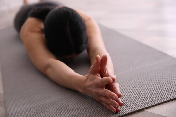 Young woman practicing extended child's asana in yoga studio, closeup. Utthita Balasana pose - Foto, afbeelding