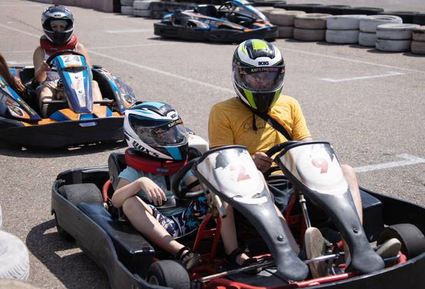 ODESSA, UKRAINE - August 7, 2022: Healthy lifestyle. Sport family. Family vacation at karting track. Children with parents go in for motorsports. Karting. Hobbies, sports education, leisure, lifestyle - Zdjęcie, obraz