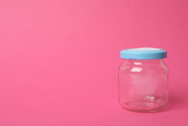 Closed empty glass jar on pink background, space for text - Фото, изображение