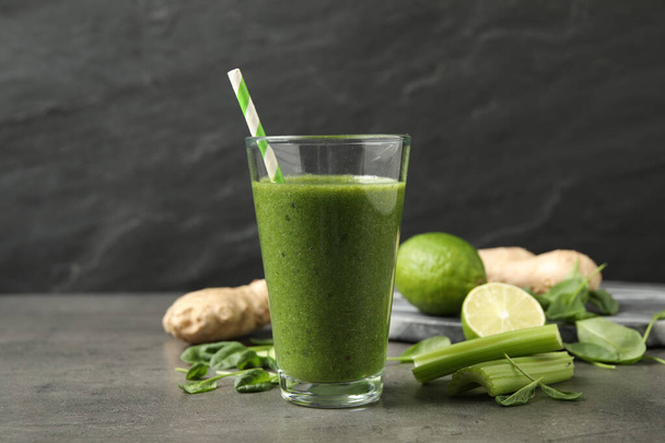 Green juice and fresh ingredients on grey table - Foto, afbeelding