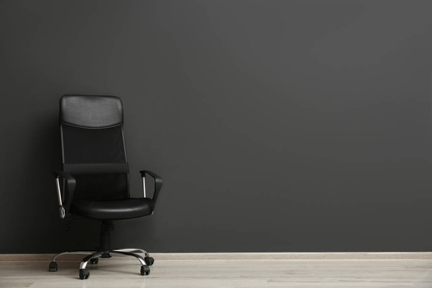 Comfortable office chair near black wall indoors. Space for text - Фото, зображення