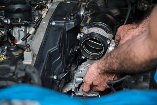 Car mechanic hands replacing engine throttle body. Mechanics workshop. - Фото, изображение