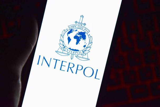Kharkiv, Ukraine - Juny 16, 2022: Person holding smartphone with Interpol logo displayed on screen. International Criminal Police Organization or Interpol. - Zdjęcie, obraz