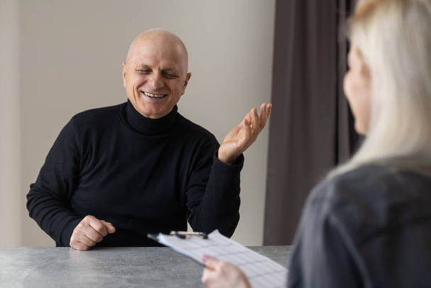 Portret kobiety psychiatry przeprowadzającej wywiad ze starszym mężczyzną podczas sesji terapeutycznej, przestrzeń do kopiowania. - Zdjęcie, obraz