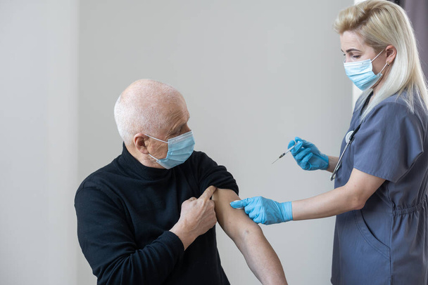 İtici Coronavirüs. Doktorun elinde bir şırınga. Bir adama covid-19 koronavirüs aşısı enjekte ediyor.. - Fotoğraf, Görsel