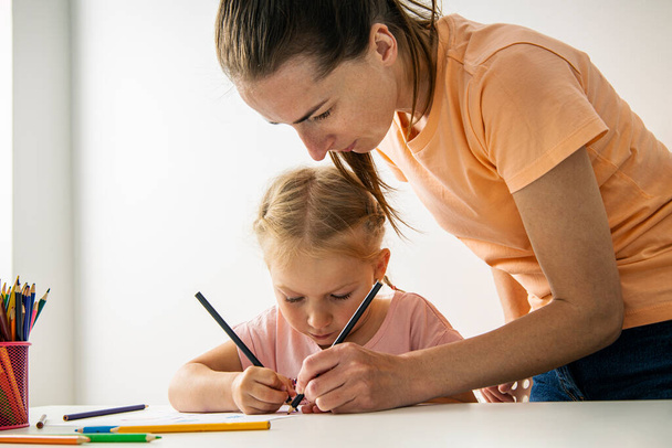 Child girl with mom draw with colored pencils on white paper. - Valokuva, kuva