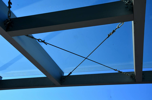 strut, suspended glass roof above the building entrance. bus station, railway station. cable wind braces. aluminum construction with windows above the pergola - Fotó, kép