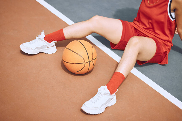 Fitness, sports and woman on basketball court floor for a break after playing a game alone in the summer. Fashion, cool and healthy athlete on the ground after training, wellness and cardio exercise. - Foto, Imagen