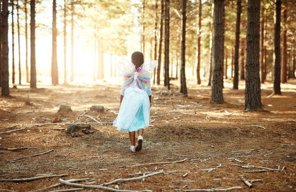 Φτερουγίζει μέσα στο δάσος. Οπίσθια εικόνα ενός μικρού κοριτσιού που περπατούσε στο δάσος ενώ ήταν ντυμένη σαν νεράιδα. - Φωτογραφία, εικόνα