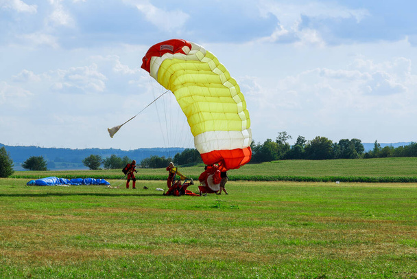 The parachutist successfully landed on the green grass. Athlete loves air sports and entertainment. - Foto, immagini