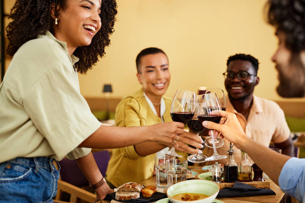 Multicultural friends toast with wine in the restaurant during dinner. - Foto, Bild