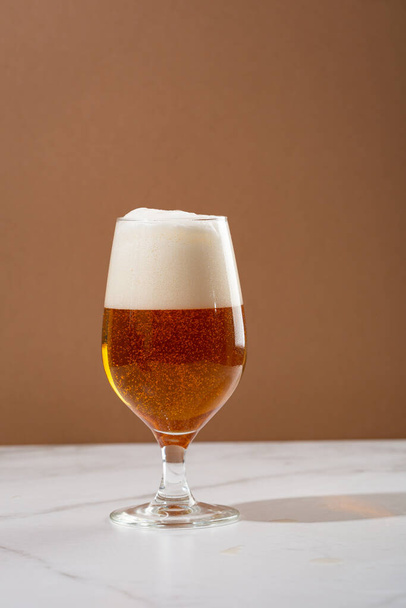Close up of glass of light beer with foam on top  food and drink copy space - Фото, изображение