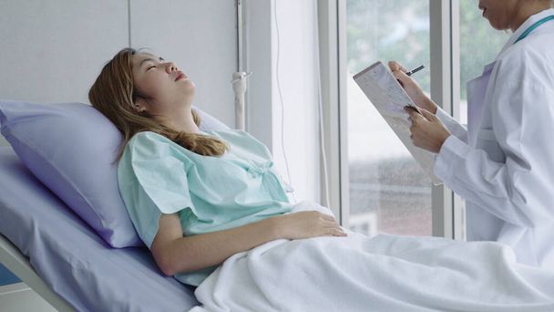 Молодая пациентка слушает результаты обследования врача на больничной койке - Фото, изображение