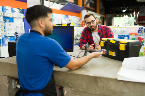 Caucasian male customer buying a tool box at the hardware store while taking with an employee at the checkout - Fotoğraf, Görsel