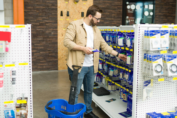 Handsome man in his 20 buying a new switch at the hardware store while doing a home improvement project  - Fotó, kép