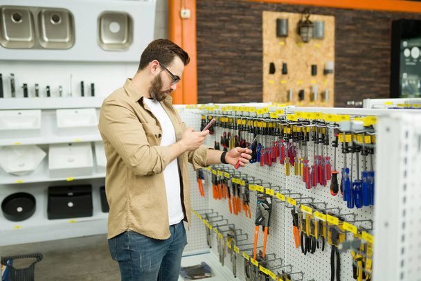 Чоловічий клієнт фотографує смс зі смартфоном на новий перемикач під час покупки в магазині обладнання
 - Фото, зображення