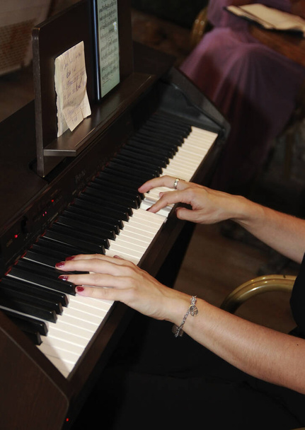 женские руки играют музыку на белых и черных клавишах пианино - Фото, изображение