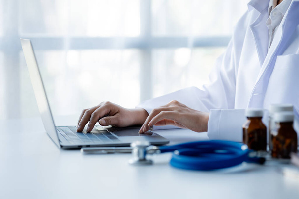 Doctors print treatment reports onto laptops in the hospital room, treating diseases from specialists and providing targeted treatment. Concepts of medical treatment and specialists. - Foto, afbeelding