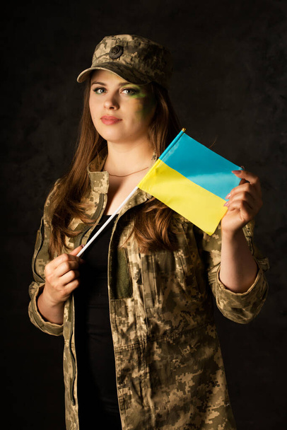 Young woman with camouflage makeup on a dark background - Photo, image