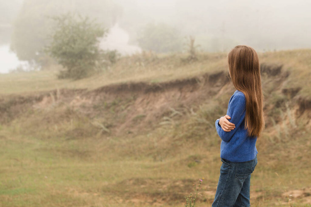 A beautiful young girl was alone in nature in a foggy morning - Foto, afbeelding