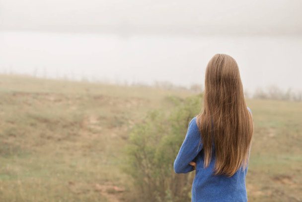 A beautiful young girl was alone in nature in a foggy morning - 写真・画像