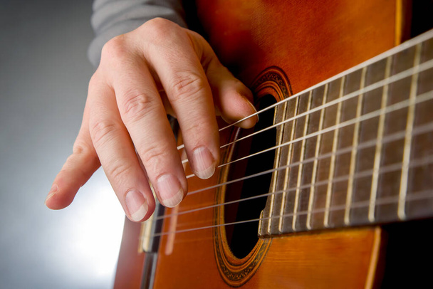 man plays the classical guitar. string musical instrument. hands of the musician playing on classical guitar - Fotó, kép