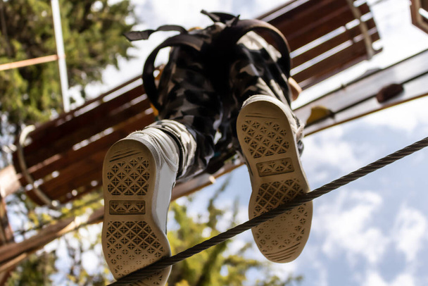 Close-up of kid walking on a hanging rope in adventure park. - Fotoğraf, Görsel